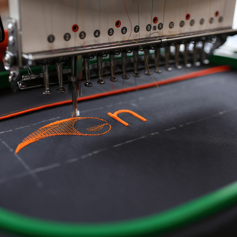 Embroidery machine stitching a design onto fabric using coloured thread.