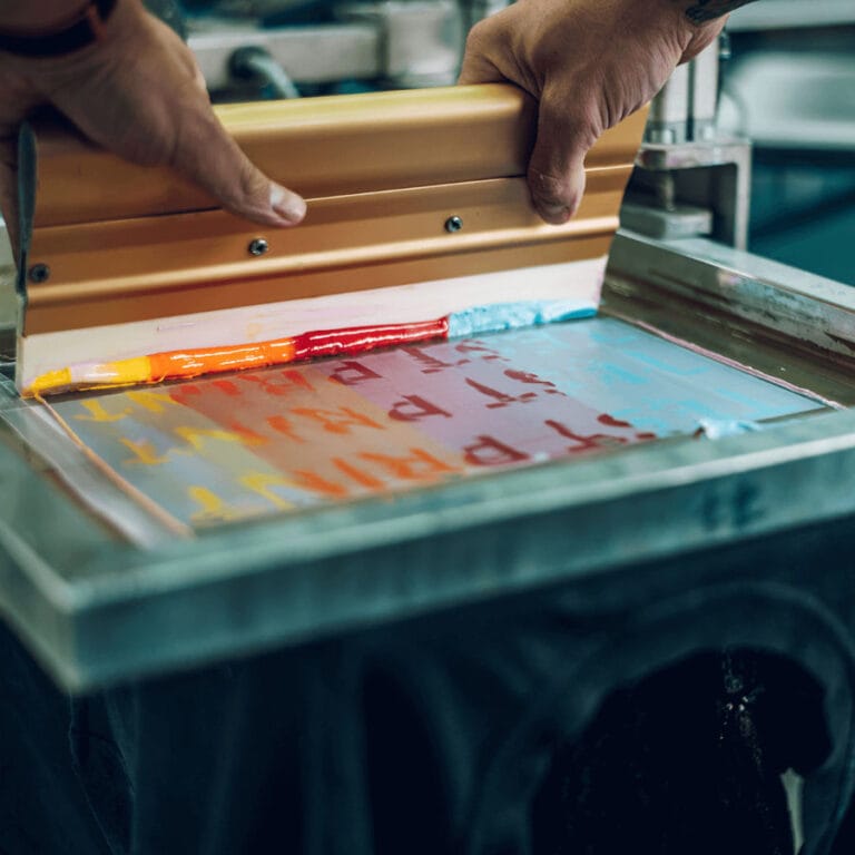Screen printing process - ink being pushed through a mesh screen using a squeegee to transfer a design onto fabric.