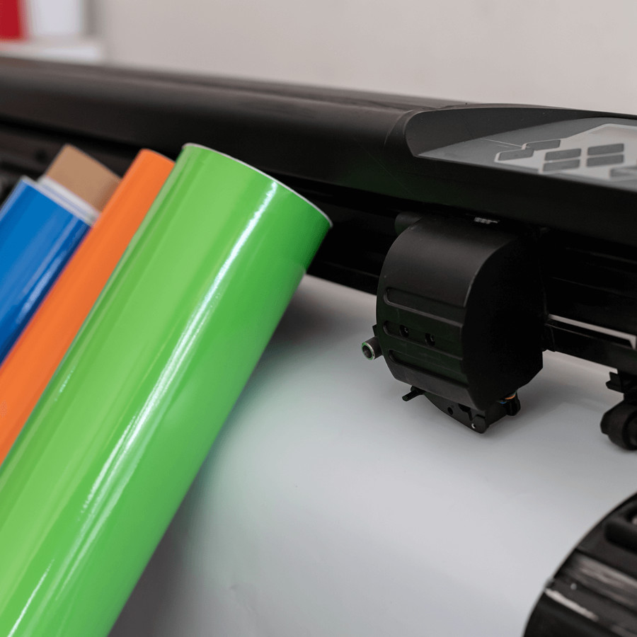 Coloured vinyl rolls next to a vinyl cutting machine.