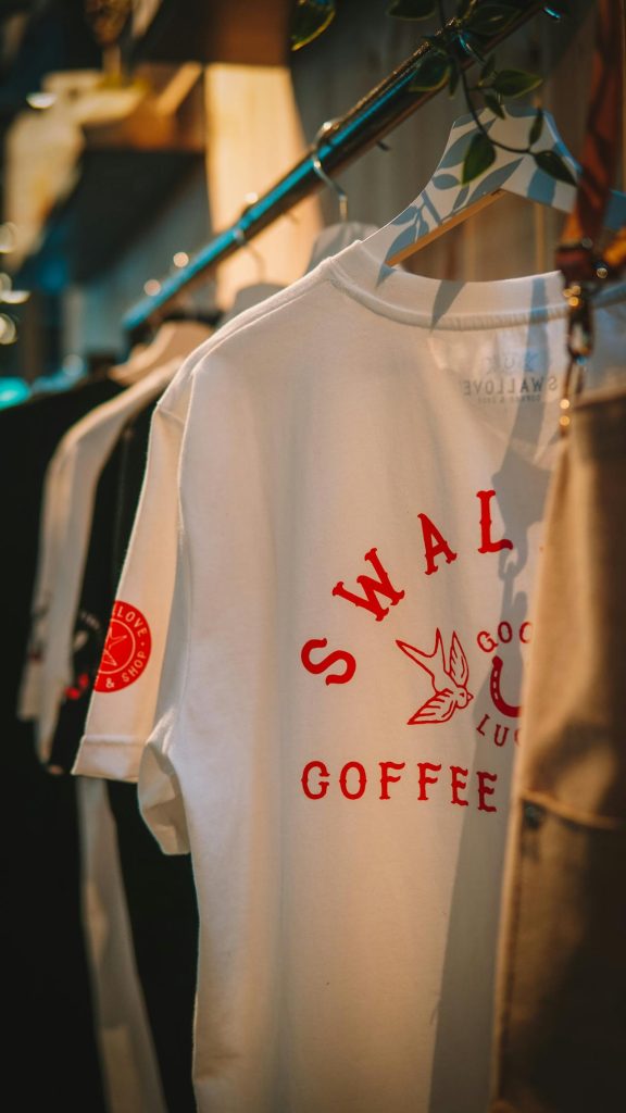 Custom printed t-shirt with red text hanging on clothing rack.