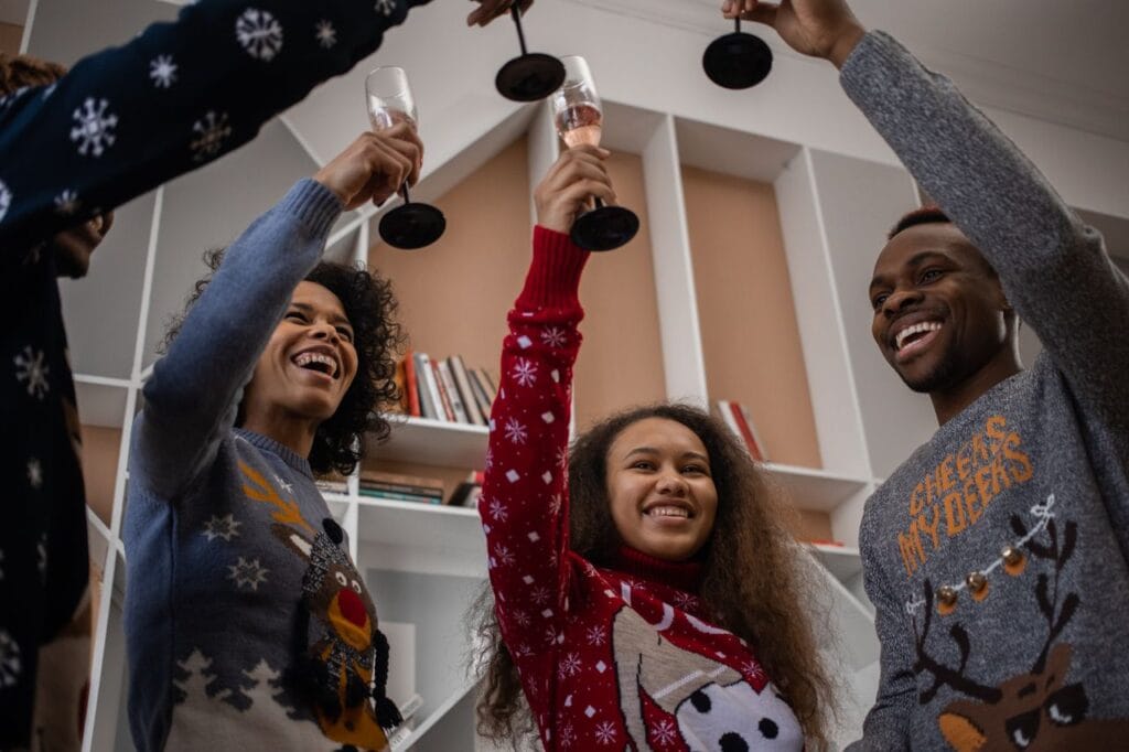 Friends in Christmas jumpers raising a toast to celebrate Christmas Jumper Day.